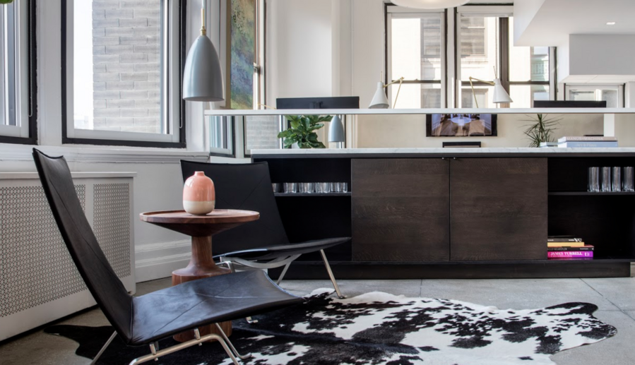 Sitting area with black leather chairs, cowhide rug, and natural light enhancing interior design details.