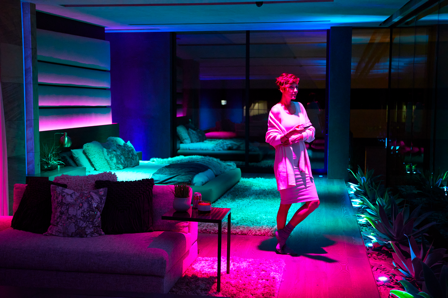 A woman is pictured in a luxury condominium with colorful mood lighting.