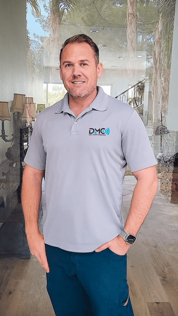 A modern, single-story house with a black and white facade, surrounded by palm trees, seen from the front.