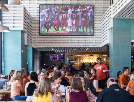 A busy restaurant with two displays, including a Screen Innovations Zero Edge Pro TV.