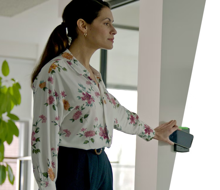 A professional using Alarm.com&rsquo;s smart access control system to unlock a secure business entrance with a mobile credential for seamless entry.