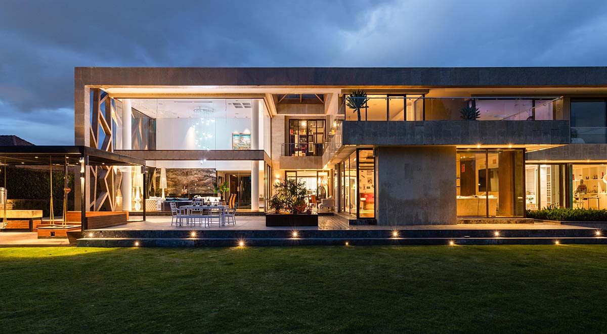 A modern, well-lit luxury home at dusk showcasing Alarm.com&rsquo;s automated lighting and security systems for enhanced safety.
