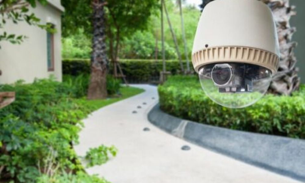 <span class="uk-h4">A driveway in the background with a home security camera in the foreground.</span>