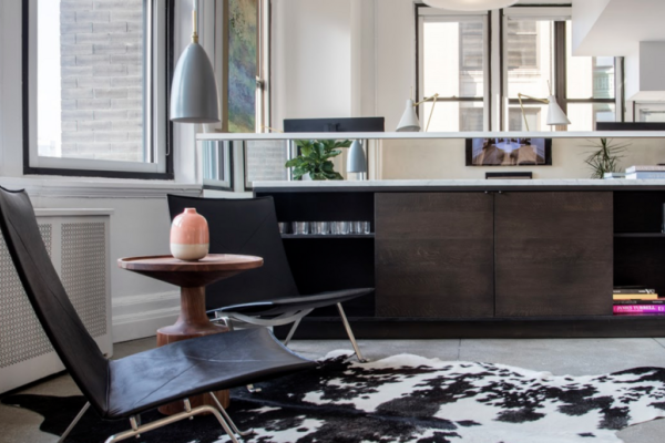 Sitting area with black leather chairs, cowhide rug, and natural light enhancing interior design details.