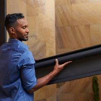 Savant shading installer holding a Savant roller shade to install in a luxury home.