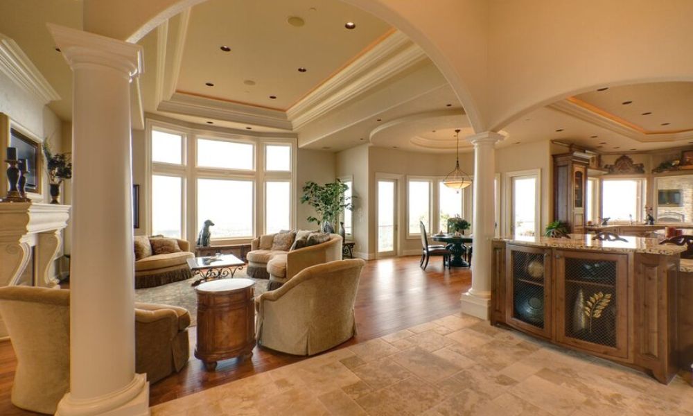 <span class="uk-h4">An open living space featuring in-ceiling whole-home audio speakers and a media room setup next to a kitchen area.</span>