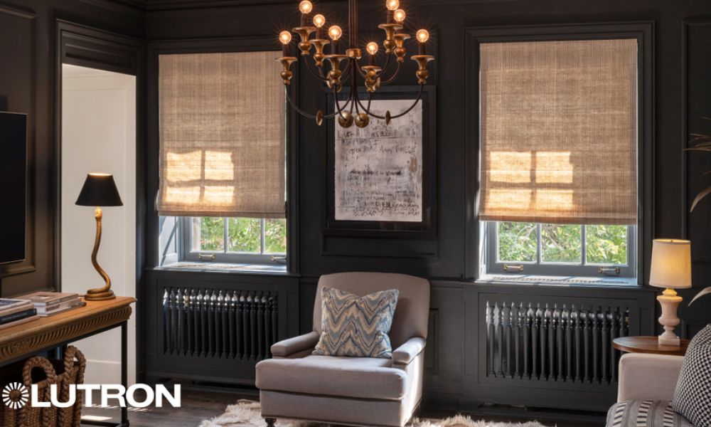 <span class="uk-h4">A cozy, elegant living room with dark walls features motorized Lutron shades partially drawn over tall windows, a classic chandelier, and a plush armchair centered below framed artwork.</span>