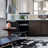 Sitting area with black leather chairs, cowhide rug, and natural light enhancing interior design details.