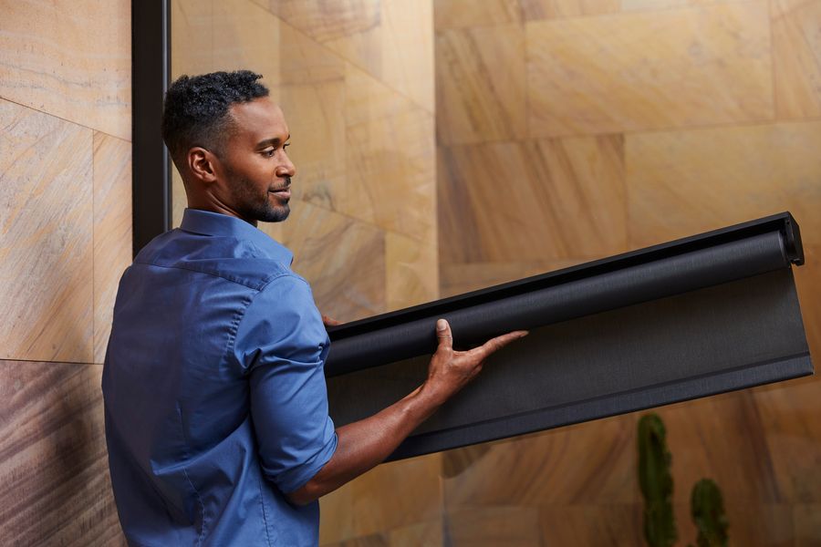 Savant shading installer holding a Savant roller shade to install in a luxury home.
