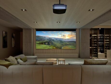 A casual home theater with a large screen, Sony projector, sectional, and wine bar.