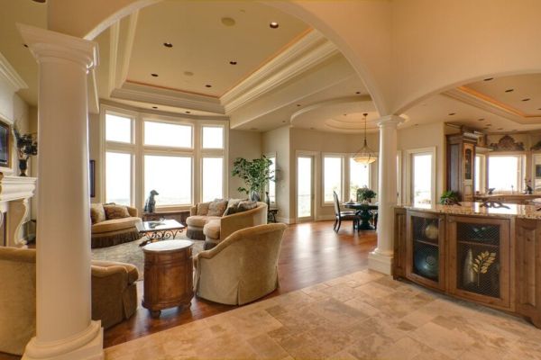 An open living space featuring in-ceiling whole-home audio speakers and a media room setup next to a kitchen area.