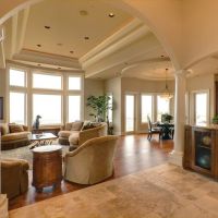 An open living space featuring in-ceiling whole-home audio speakers and a media room setup next to a kitchen area.