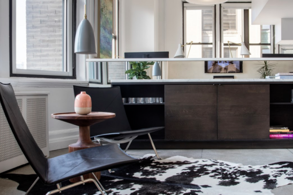 Sitting area with black leather chairs, cowhide rug, and natural light enhancing interior design details.