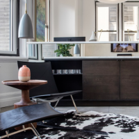 Sitting area with black leather chairs, cowhide rug, and natural light enhancing interior design details.